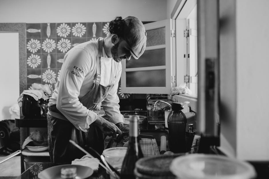 Chef in a kitchen preparing a meal, captured in black and white for a classic feel.
